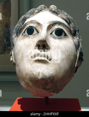 Masque d'une femme avec une grande bobine de cheveux tressés A.D. 117–138 période romaine, Hadrien les masques en plâtre dérivent des traditions pharaoniques, dans lesquelles le masque a servi de substitut à la tête du défunt et comme moyen de l'élever au statut immortel.La dérivation se reflète souvent dans les peintures et les textes situés sur le manteau entourant la tête.Tout comme les portraits de momies peints, les masques suggèrent des apparences fortement individualisées et affectent les modes romains dans la coiffure, les bijoux, et la robe.Ils suivent cependant un modèle quelque peu différent.Par exemple, les masques féminins peuvent hav Banque D'Images