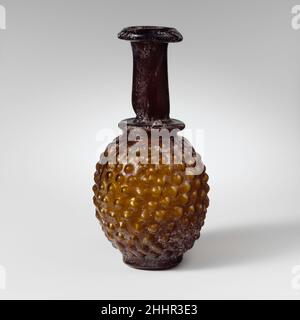 Bouteille en verre en forme d'un bouquet de raisins ca.3rd Century A.D. Roman, syrien translucide miel brun.Rim plié, vers le bas, vers le haut et vers le haut, avec rebord extérieur biseauté; col cylindrique avec outil horizontal indentation autour de la base; épaule horizontale légèrement enfoncée avec rouleau de projection creux en dessous; corps ovoïde; base cylindrique basse, avec fond plat.Cicatrice Pontil au centre du fond.Corps soufflé dans un moule en trois parties de deux sections verticales, s'étendant de la base à l'épaule, et une section de base en forme de disque.sur le corps, un modèle de raisins stylisés comprenant onze rangées de vingt-deux unevenl emboîtées Banque D'Images