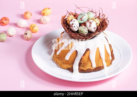Gâteau de Pâques avec œufs colorés dans un nid au chocolat sur fond rose.Concept joyeuses Pâques.Dessert également connu sous le nom de Kuglof. Banque D'Images