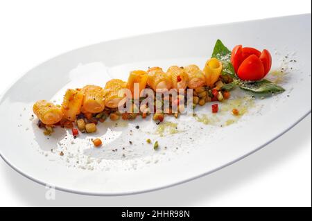 Faire mezze des pâtes de maniche avec sauce tomate sur des légumes cuits coupés avec des tomates cerises et des feuilles de basilic dans une assiette blanche isolée sur fond blanc, copie s. Banque D'Images