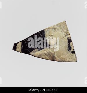 Fragment de plaque de caméo en verre 1st Century A.D. Roman translucide violet profond avec revêtement blanc opaque.face inférieure plate; surface légèrement ondulée avec décoration de relief;Petite section du bord gauche avec lèvre supérieure arrondie. En relief en blanc, la tête de la figure tournée vers la gauche, avec de longs cheveux ondulés dissimulant l'oreille droite, portant une tunique en larges bandes sur les épaules; derrière la partie droite de l'épaule gauche d'un objet non identifié;À gauche de la figure, partie d'une longue équipe.brisée sur trois côtés avec des bords abîmés; de nombreuses fissures de déformation interne; morcellement, piqûres légères, taches de noir épais et de bril Banque D'Images