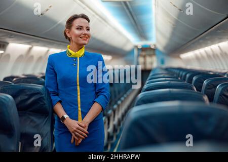 Un employé de bord joyeux debout dans la cabine passager de l'avion Banque D'Images