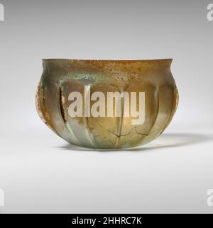 Bol en verre nervuré mi-1st Century A.D. Roman translucide bleu pâle vert.renfoncé, rebord inégal; col concave court; côté bombé courbé vers le fond plat.outil latéral en quatorze nervures verticales irrégulières.cassé avec des parties de rebord manquantes et un petit trou sur le côté; quelques bulles; morcellement, piqûres profondes et taches d'intempéries laiteuses épaisses.Bol en verre nervuré 239849 Banque D'Images
