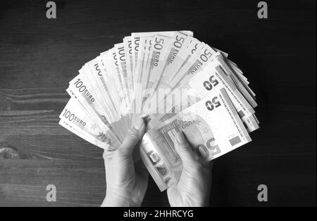 Pack monochrome de billets en euros dans la main de la femme sur toile de fond en bois Banque D'Images