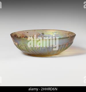 Bol en verre nervuré fin du 1st siècle C.-B.–milieu du 1st siècle A.D. Roman ColorlessRent à bord biseauté; les côtés se courbent vers le bas pour former un fond légèrement concave.a l'intérieur, deux rainures concentriques autour du bord du fond et un petit cercle au centre;À l'extérieur, cinquante nervures obliques de longueur et d'épaisseur irrégulières, avec des surfaces meulées. Intactes, à l'exception des petites copeaux altérés dans le rebord; de nombreuses bulles de piqûres; piqûres, morcellement et intempéries irisées.marques de meulage rotatives à l'intérieur et sur la bande autour de l'extérieur.Bol en verre nervuré 239866 Banque D'Images