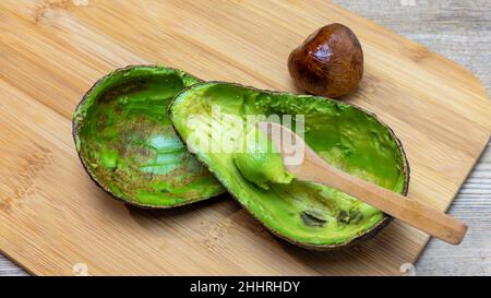 avocat coupé et vidé de pulpe avec une cuillère en bois sur planche à découper en bambou, sans gluten, panorama Banque D'Images