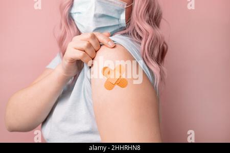 Jeune femme caucasienne portant un masque protecteur contre le covid-19 montrant l'épaule après l'obtention du vaccin.Dose de rappel, passeport vaccinal. Banque D'Images