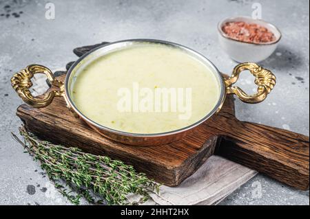 Le vichyssois est une soupe traditionnelle française préparée dans une casserole avec du poireau, de la pomme de terre et de l'oignon.Arrière-plan gris.Vue de dessus Banque D'Images