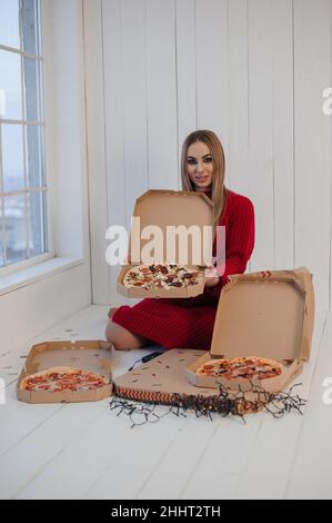 Fille dans une robe rouge tenant une pizza Banque D'Images