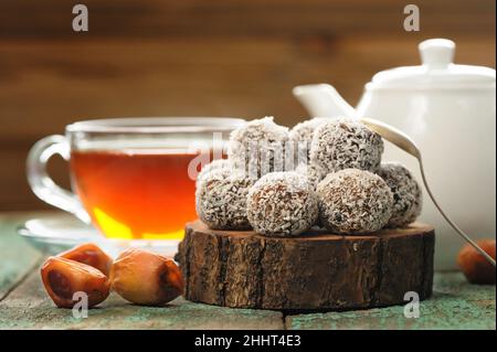 Bonbons faits maison aux dattes végétaliennes aux noix de coco servis avec du thé noir en gros plan Banque D'Images