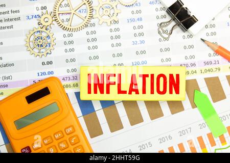 Real - BRL le mot inflation écrit en portugais brésilien sur des cubes en bois sur une table en bois.Billets réels brésiliens et calculatrice bleue dans le i Banque D'Images