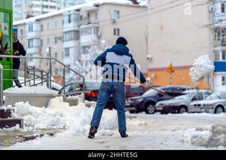 Krasnodar, Russie - janvier 24 2022 : enlèvement de l'homme neige avec une Shovel.Pelletage de la rue de la neige qui tombe Banque D'Images