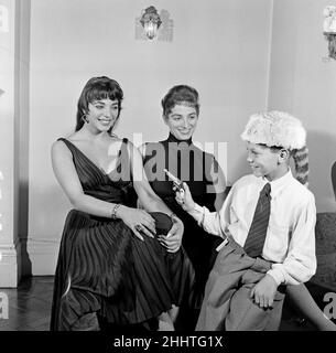 Joan Collins, actrice, âgée de 22 ans, photographiée avec une robe de cocktail en soie noire, à son appartement à Marylebone, Londres, le 10th février 1954.Photo-appel après 10 mois de séjour à Hollywood.Photo avec la jeune sœur Jackie Collins et le frère Bill Collins, portant le chapeau Davy Crockett. Banque D'Images