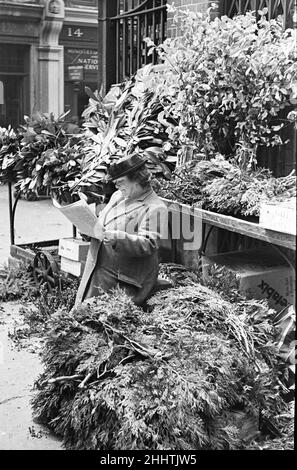 Journée dans la vie de Covent Garden Market Cirica 1948London, Angleterre.Une dame de fleur avec ses fleurs a une lecture de son papier entre ses clients quotidiens.Photo prise le 1st juillet 1948 Banque D'Images