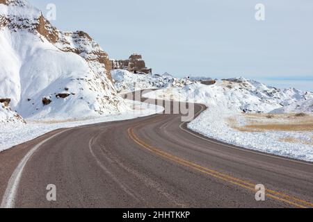 Route sinueuse à travers le parc national de Badlands, Dakota du Sud dans la neige d'hiver Banque D'Images