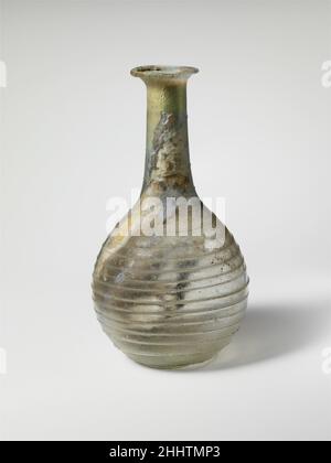 Flacon de parfum en verre 1st Century A.D. Roman incolore, avec sentier en blanc opaque avec une teinte verdâtre. Rebord éverté replié et intérieur; col cylindrique, extensible vers le bas; corps globulaire;Pousser-dans le fond.Trail appliqué sur le fond, puis enroulé sur le corps dans une spirale dix-neuf fois, se terminant sur le haut du cou en dessous de rim.Complete, mais fissures dans le corps; des bulles d'épingle et une impureté noire dans le sentier;le revêtement extérieur est terne et les intempéries sont atténuées, les taches de sol épais sont enrobantes et l'intérieur est très brillant.Flacon de parfum en verre 245349 Banque D'Images