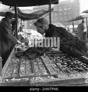 Femme au foyer parcourant les étals antiques du marché de la rue de New Caledonian pour les bijoux.22nd mars 1954 Banque D'Images