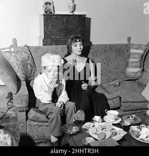 Joan Collins, actrice, âgée de 22 ans, photographiée avec une robe de cocktail en soie noire, à son appartement à Marylebone, Londres, le 10th février 1954.Photo-appel après 10 mois de séjour à Hollywood.Photo avec le jeune frère Bill Collins, portant le chapeau Davy Crockett. Banque D'Images