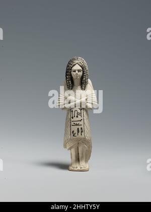 Shabti du Scribe Huy portant un Bat-pendentif ca.1295–1185 C.-B. Nouveau Royaume, Ramesside Shabtis étaient de petites figures magiques déposées dans une tombe pour répondre pour le défunt s'il ou elle devait être appelé à faire du travail dans l'après-vie.Cette figure dépeint Huy comme il était dans la vie : vêtu d'une tunique plissée à la mode et d'un châle enveloppant et portant une amulette associée à la déesse Hathor autour de son cou.Sa perruque est d'un type qui semble avoir été populaire à la fois auprès des scribes et du personnel militaire pendant la dynastie de la fin de 18th.Shabti du Scribe Huy portant un Bat-pendentif. CA.1295–1185 B.C Banque D'Images