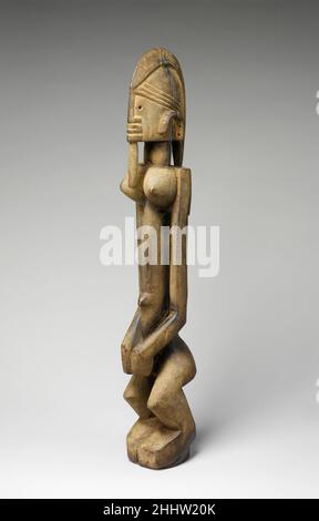 Figure: Femme (Dege Dal NDA) 18th–19th siècle Maître d'Ogol cette figure féminine est l'une des environ une douzaine d'œuvres qui ont été attribuées au même artiste Dogon,Identifié par les historiens de l'art comme le Maître d'Ogol après un village dans la région de Sanga où une œuvre dans ce corpus a été collectée en 1935.La forme de la tête et les traits faciaux des œuvres créées par le Maître sont distinctifs pour la tête helmétlike et l'unique ensemble de bouche-narines-menton empilé horizontalement, étroitement encadré par le nez vertical fort et la lèvre d'ornement cylindrique.Œuvres identifiées comme DEGE dal nda, ou 'Sculptur Banque D'Images