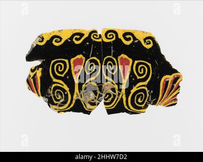 Incrustation en mosaïque de verre 1st siècle avant J.-C.–1st siècle avant J.-C. Egyptien, romain, violet profond, apparaissant en noir; décoration en jaune et rouge opaque.plaque rectangulaire, mince et plate, avec des bords légèrement biseautés.motif symétrique lotus et palmette, avec deux longues fleurs de lotus flanquées de doubles volutes en spirale et deux palmettes à chaque extrémité;Ci-dessus, motif d'onde continue.cassé et réparé avec des trous et des fissures, et des bords irréguliers; côté supérieur rectifié et poli; bulles de surface piquées, altération sur les bords et arrière.l'incrustation est faite de deux sections coupées de la même canne de verre de mosaïque, avec décoration Banque D'Images