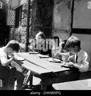 Dans le repos des pèlerins, l'ancienne auberge Tudor à l'extérieur du château de bataille sont 5 enfants qui prennent leur repas à l'école.Ils et leurs camarades d'école y ont leur repas scolaire tous les jours.De gauche à droite, Jane Goodwin 9, Isabelle de Villier-Guimbieu 8, Mary Taylor 5, David Lovelock 7 et Alexander Wagstaff 9.Les enfants sont de l'école gay Bows.Battle, East Sussex, 21st juillet 1954.dans le repos des pèlerins, l'ancienne auberge Tudor à l'extérieur du château de bataille sont 5 enfants qui prennent leur repas scolaire.Ils et leurs camarades d'école y ont leur repas scolaire tous les jours.De gauche à droite, J Banque D'Images