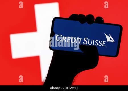 Smartphone avec logo de la banque Credit Suisse dans la main sur fond de drapeau suisse Banque D'Images
