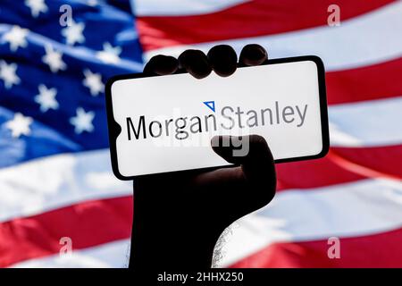 Smartphone avec logo Morgan Stanley Bank dans la main sur le fond du drapeau américain Banque D'Images