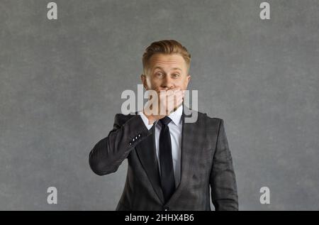 Portrait d'un homme d'affaires surpris couvrant la bouche avec la main regardant l'appareil photo Banque D'Images