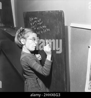 Un des élèves de l'école de South Mead, Southfield, Wimbledon vu ici pratiquer l'écriture à la main sur le tableau noir.14th janvier 1954 Banque D'Images