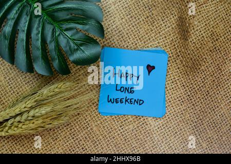 Happy long week-end écrire sur les notes adhésives isolées sur la table en bois. Banque D'Images