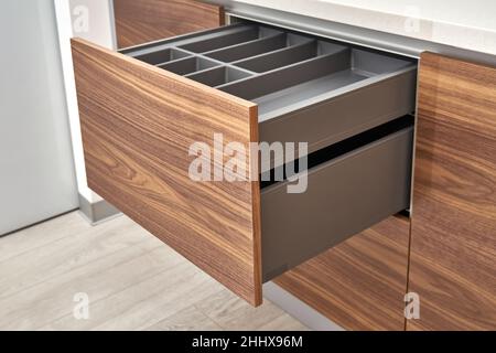 Tiroirs ouverts de couleur gris foncé avec plateau à couverts dans une cuisine contemporaine en bois de noyer et de couleur grise avec plan de travail en acrylique à surface solide Banque D'Images