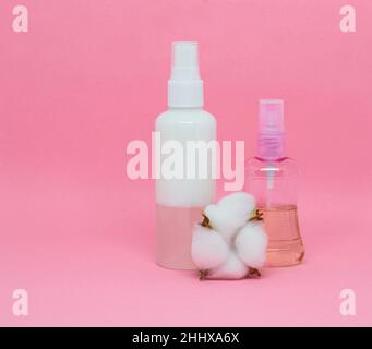 Deux vaporisateurs et une fleur de coton sur fond rose. Placer pour le texte Banque D'Images