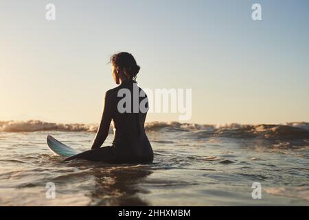 Elle est aussi calme que l'océan.Photo d'une jeune femme surfant dans l'océan. Banque D'Images