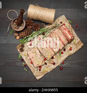 Terrine française traditionnelle en tranches recouverte de bacon sur fond de bois sombre Banque D'Images