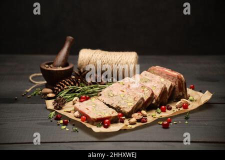 Terrine française traditionnelle en tranches recouverte de bacon sur fond de bois sombre Banque D'Images