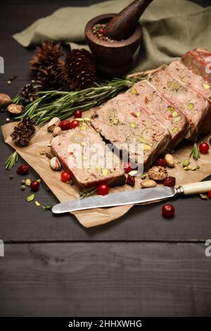 Terrine française traditionnelle en tranches recouverte de bacon sur fond de bois sombre Banque D'Images