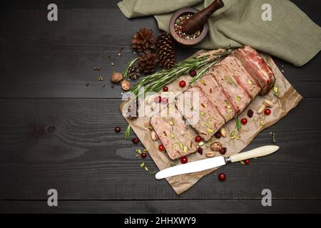 Terrine française traditionnelle en tranches recouverte de bacon sur fond de bois sombre Banque D'Images