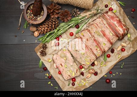 Terrine française traditionnelle en tranches recouverte de bacon sur fond de bois sombre Banque D'Images
