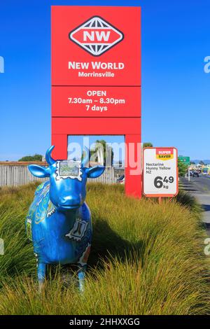 Une sculpture d'une vache et un panneau de supermarché du Nouveau monde à Morrinsville, en Nouvelle-Zélande.Les nombreuses sculptures de vache de la ville sont une attraction touristique Banque D'Images