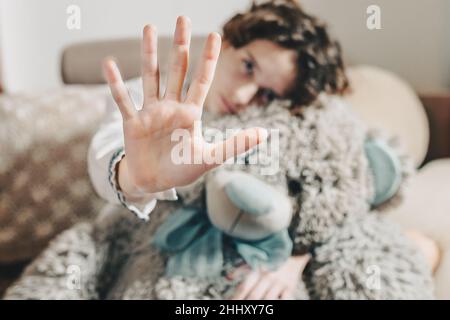 une adolescente en chemise blanche brodée ethnique, avec des poils marrons, se tient près de l'ours en peluche, en mettant la main en avant. concept no aux violons domestiques Banque D'Images