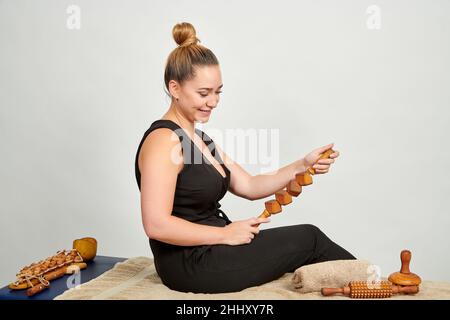 Une jolie masseuse caucasienne professionnelle avec beaucoup d'outils en bois d'un massage cellulite Banque D'Images