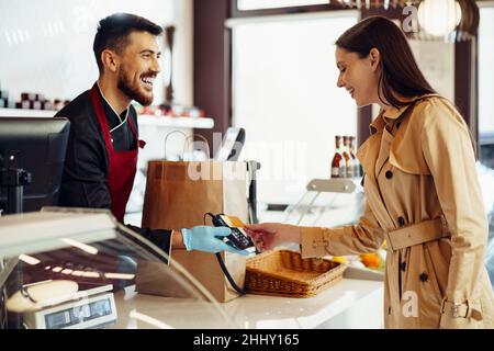 Jeune femme payant par carte de crédit pour des achats à l'épicerie. Banque D'Images