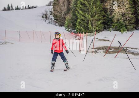 Ski enfant en montagne.Enfant actif avec casque de sécurité, lunettes et poteaux.Course de ski pour les jeunes enfants.Sports d'hiver pour la famille.Ski pour enfants Banque D'Images