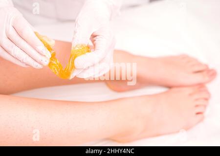 Photo en gros plan des jambes d'une femme qui a passé la procédure à sucre pour enlever les cheveux de ses jambes, soins du corps, concept spa d'épilation. Banque D'Images