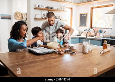 Toute la famille s'implique.Plan de coupe d'un jeune couple cuisant à la maison avec leurs deux enfants. Banque D'Images