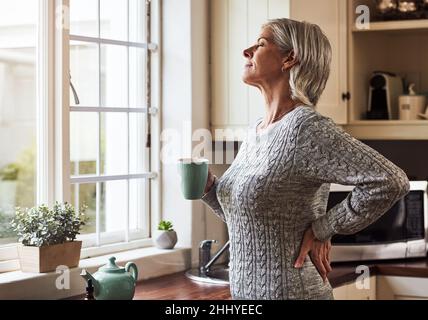 Je me sens déjà mieux.Coupe courte d'une femme sénior détendue préparant une tasse de thé avec de l'huile CBD à l'intérieur de celle-ci à la maison pendant la journée. Banque D'Images