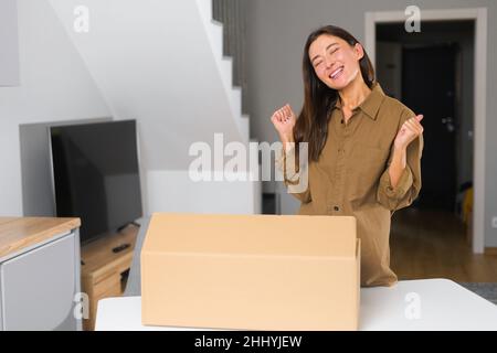 Content de livraison client femme satisfait déballage carton, excitée femme asiatique heureux d'obtenir un colis, commander en ligne, une fille surjoyée à la maison Banque D'Images