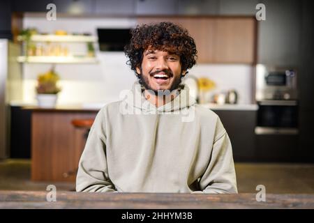 Travail de bureau.Portrait d'un jeune homme beau dans des vêtements domestiques élégants et décontractés.Il est assis à la table et regarde la caméra avec plaisir sourire.Photo horizontale Banque D'Images