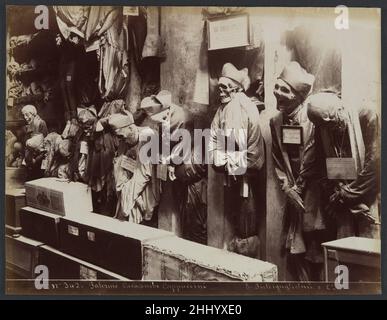 Catacombes, Convento dei Cappucini, Palerme ca.1895 Eugenio Interguglielmi plus de huit mille cadavres embaumés bordent les murs du couvent des capucins de Palerme, en Sicile.Ils sont organisés par sexe, âge et même profession, selon la même classe et les mêmes hiérarchies sociales qui ont façonné leur vie.Ici, une lumière aveuglante brille sur des rangs de clergé décorés dans leurs plus beaux vêtements, donnant vie au spectacle de la mort.La crypte était déjà une destination touristique populaire au XIXe siècle, et des photographies comme celle-ci ont offert aux visiteurs un souvenir macabre de ce qu'un contemporain Banque D'Images